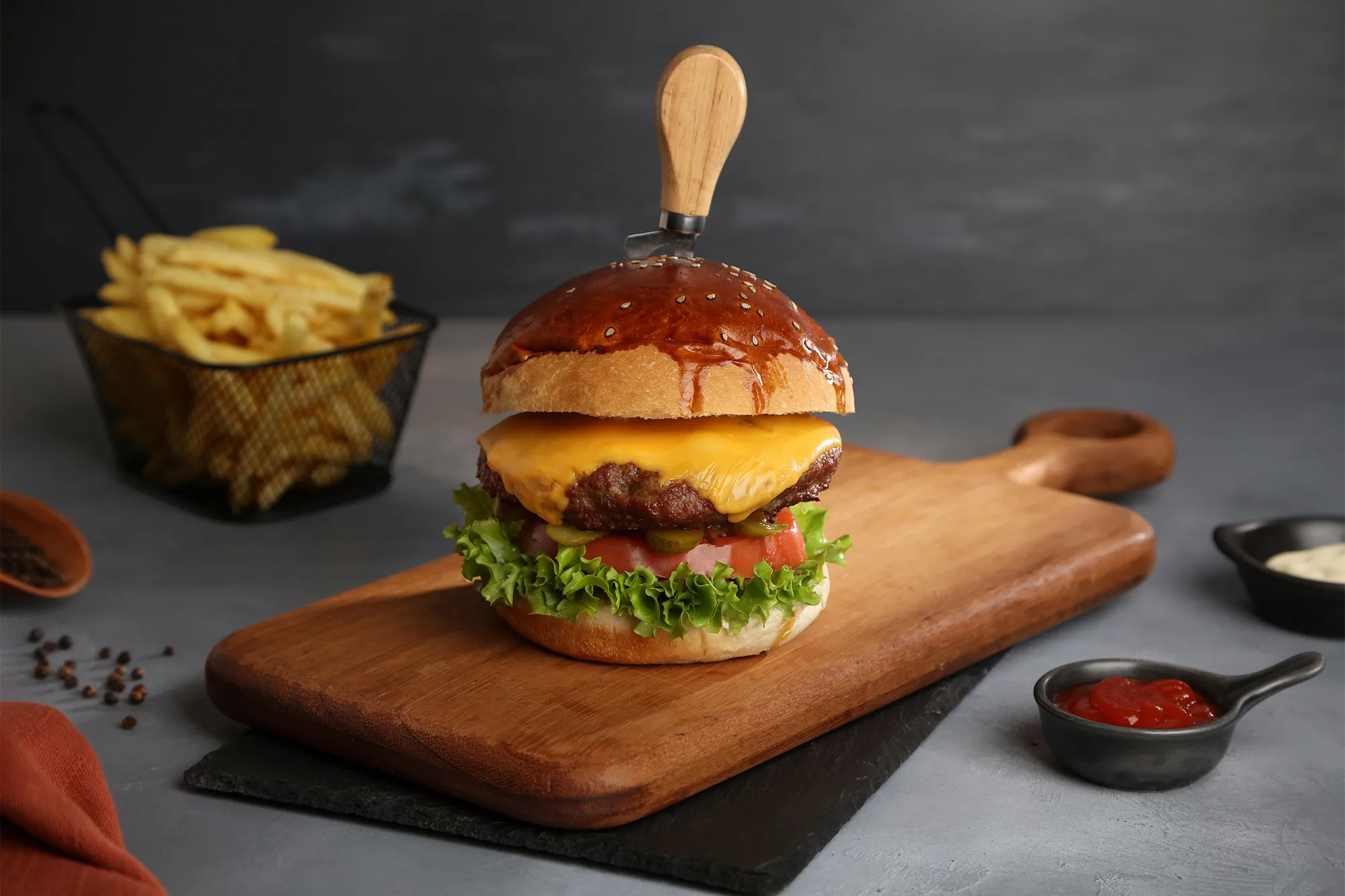 Bir hamburger fotoğrafı, patates kızartması ve dekoratif bir masa örtüsü.